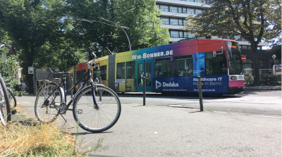 Fahrrad im Vordergrund und eine vorbeifahrende Straßenbahn im Hintergrund